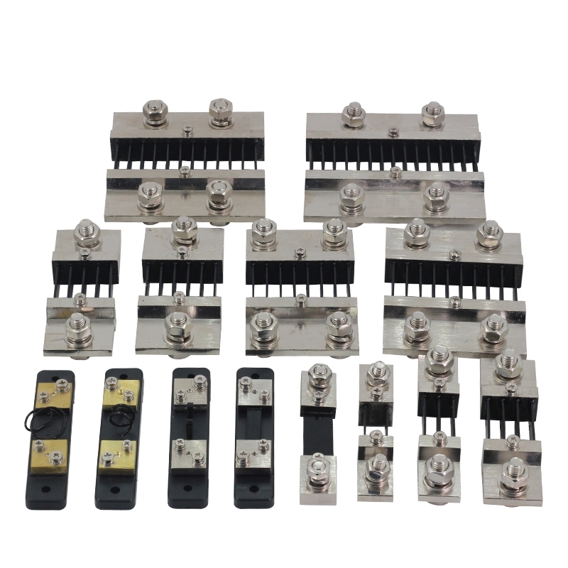 The alternative text for this image could be: "An assortment of DC shunts, which are precision resistors used to measure current flow in ammeters, displayed against a white background. These components vary in size, indicating their different current ratings, and are made of a beige insulating material with metal strips and screws for electrical connections."