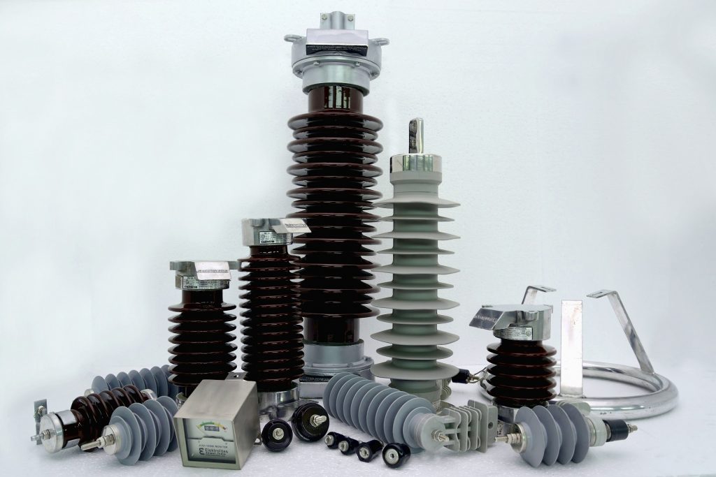 A collection of lightning arresters in various sizes and designs, including porcelain and polymer-housed models, used for electrical surge protection in power systems.
